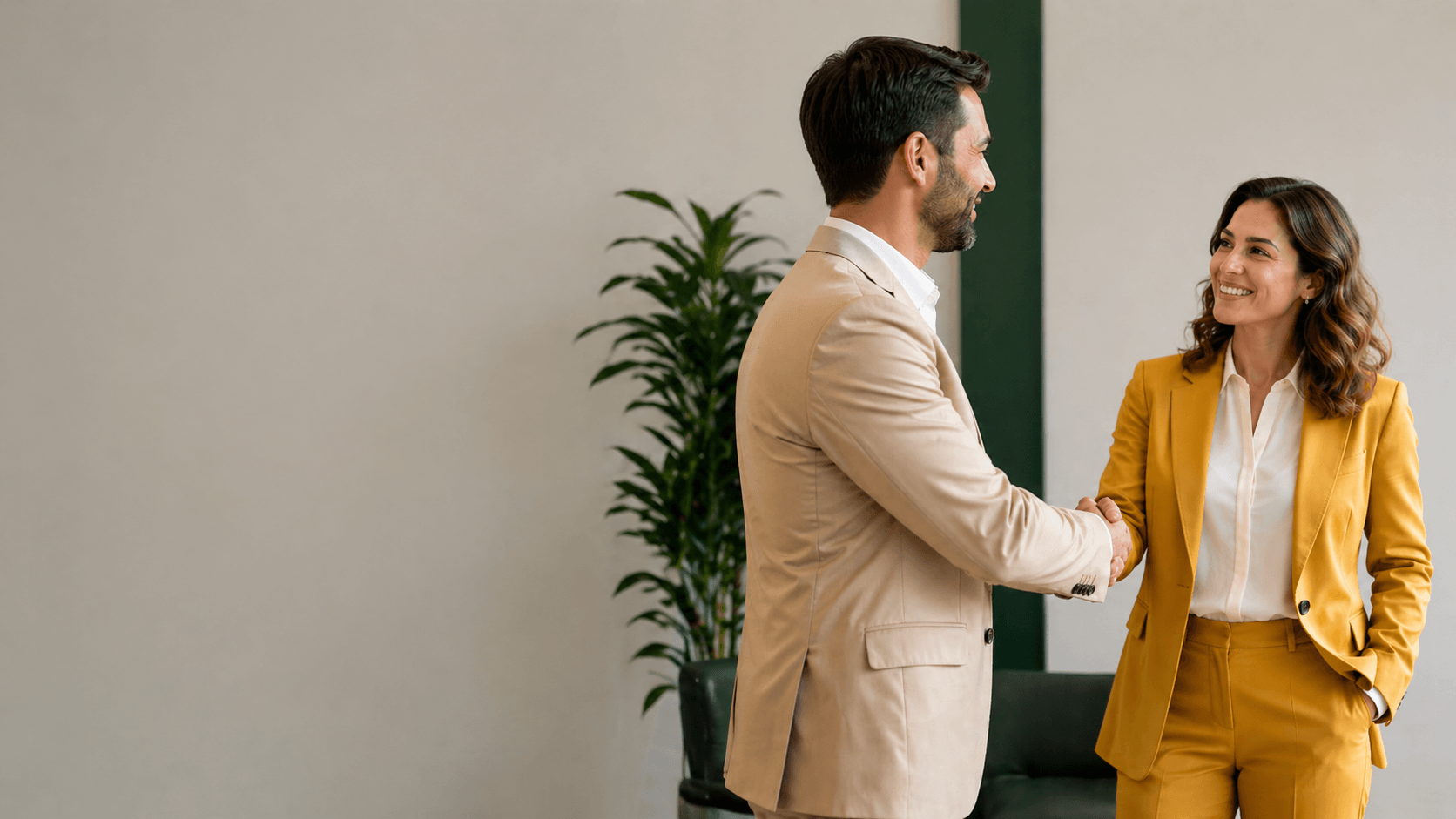 Homem e mulher em ambiente corporativo apertando as mãos durante uma reunião de negócios, representando parceria, confiança e relacionamento profissional.